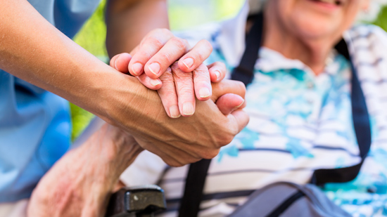 nurse consoling senior woman holding her hand