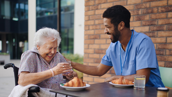 caregiver having breakfast with his client at cafe