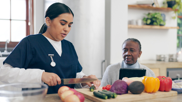 nurse, cooking and senior woman in home with healthy food, vegetables and nutrition in healthcare